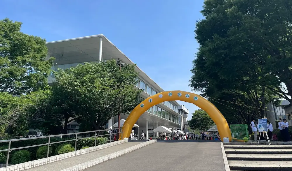 青空の下、大学のキャンパスに黄色い大型のバルーンゲートが設置されている